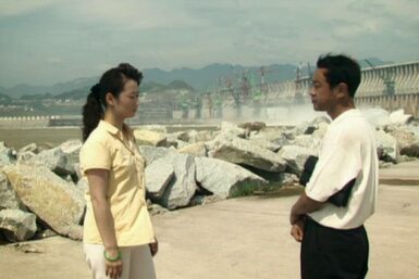 A man and woman face each other in front of a pile of rubble